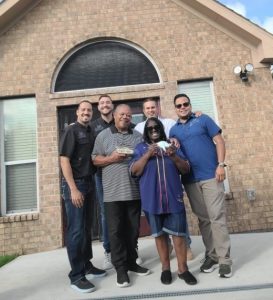 Inc. team with veterans standing in front of a residential home in Houston, highlighting collaboration and support for veteran home adaptation projects.